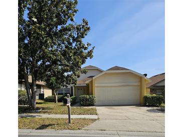 Charming single-Gathering home featuring a two-car garage, well-maintained lawn, and mature tree at 7228 Spring Villas Cir, Orlando, FL 32819
