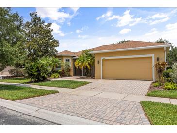 Charming home with a well-manicured lawn, lush landscaping, and a brick driveway at 187 Tall Pines Pass, Kissimmee, FL 34759