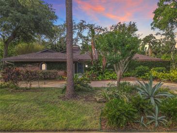 Beautiful brick home featuring lush landscaping, mature trees, and an inviting entrance at sunset at 2350 Worthington Rd, Maitland, FL 32751