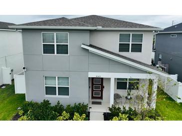 Modern two-story home with a gray exterior, front porch, and well-maintained landscaping at 8563 Compass Point Ave, Orlando, FL 32832
