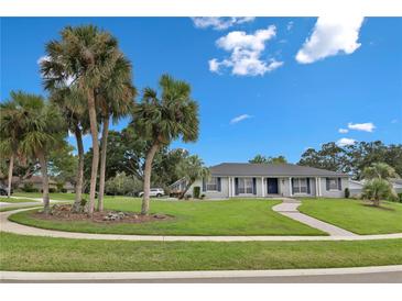 Inviting single story home featuring lush landscaping, mature palm trees, and a circular driveway at 105 Spring Cove Trl, Altamonte Springs, FL 32714