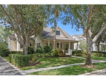 Charming home with a well-manicured lawn, mature trees, and a welcoming front porch at 11415 N Camden Commons Dr, Windermere, FL 34786