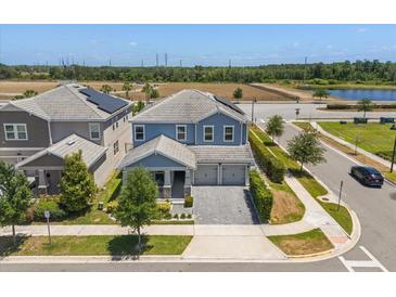 Two-story home with blue siding, a paved driveway, a manicured lawn, and solar panels at 11993 Charades St, Orlando, FL 32832