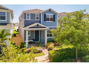 Charming two-story home with blue accents, landscaped yard, and covered front porch entrance at 15959 Pantuso Aly, Winter Garden, FL 34787
