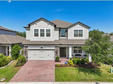 Charming two-story home featuring a brick driveway, manicured lawn and a welcoming front porch at 17226 Hickory Wind Dr, Clermont, FL 34711