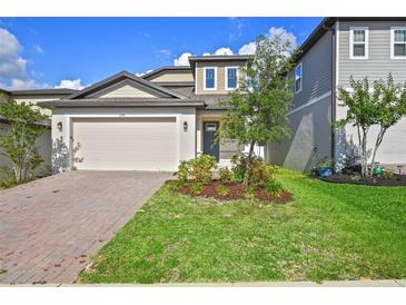 Charming two-story home featuring a brick driveway, well-manicured lawn, and attached two-car garage at 2304 Mystic Maze Ln, Clermont, FL 34715