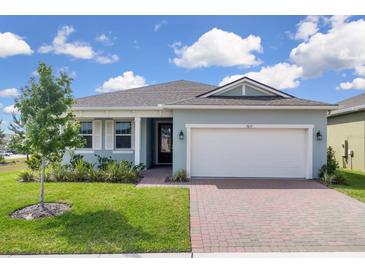 Charming single-story home featuring a manicured lawn and brick-paved driveway leading to an attached two-car garage at 3017 Ambersweet Pl, Clermont, FL 34711