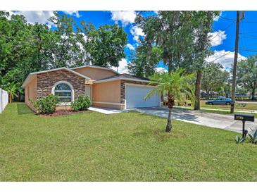 Single-story home featuring a well-manicured lawn, mature trees and an attached garage with decorative stone features at 3795 Rachel St, Apopka, FL 32703