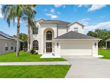 Elegant two-story home with a well-manicured lawn, lush landscaping, and a spacious two-car garage at 4751 Aguila Pl, Orlando, FL 32826