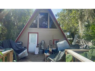 A-frame home featuring a red trim, a large window, and a covered deck at 283 Oak Ln, New Smyrna Beach, FL 32168