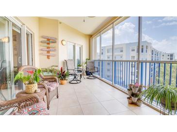 Relaxing screened balcony with seating, tile floor, and coastal-themed decor offers a charming outdoor living space at 5300 S Atlantic Ave # 6-502, New Smyrna Beach, FL 32169