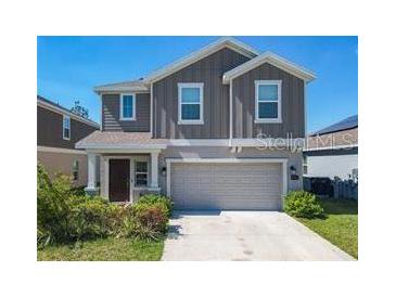 Two-story home with a two-car garage and cozy porch, highlighted by a well-maintained lawn at 942 Jackson Ave, Davenport, FL 33837