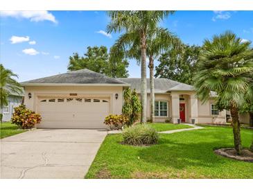 Charming single-story home with a lush lawn, mature palm trees, and a welcoming red front door at 1428 Lucky Pennie Way, Apopka, FL 32712
