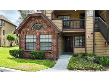Condo exterior showcasing a red brick accent wall with black trim and a well-manicured lawn and tidy landscaping at 315 Lakepointe Dr # 101, Altamonte Springs, FL 32701