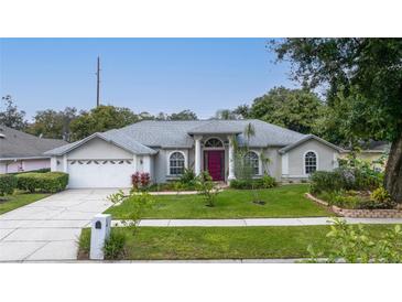 Charming single-story home with a manicured front yard, lush landscaping, and a welcoming red front door at 4265 Conway Place Cir, Orlando, FL 32812