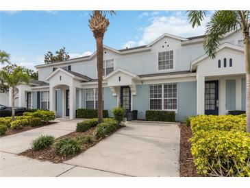 Charming light-blue townhome featuring a private driveway, manicured landscaping, and a classic facade at 7663 Fitzclarence St, Kissimmee, FL 34747
