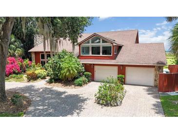 Attractive brick home with mature landscaping, two-car garage, and ample parking on circular driveway at 1093 Hidden Harbor Ln, Kissimmee, FL 34746