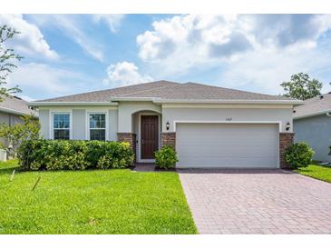 Charming single-story home featuring a well-manicured lawn, brick-accented entryway, and a two-car garage at 1167 Celery Oaks Ln, Sanford, FL 32771
