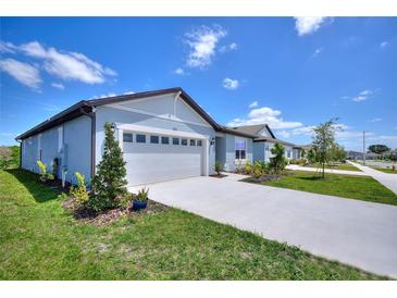Charming single-story home featuring a two-car garage and well-maintained landscaping with lush grass at 423 Pine Tree Blvd, Lake Alfred, FL 33850