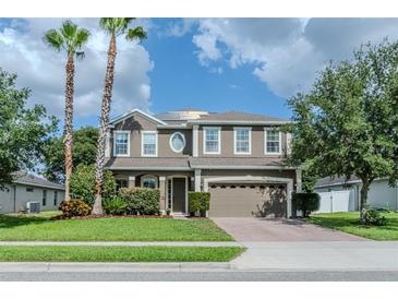 Charming two-story home with a well-manicured lawn, palm trees, and an attached two-car garage at 459 Millwood Pl, Winter Garden, FL 34787