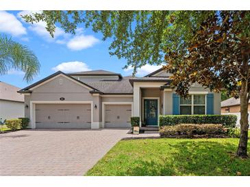 Charming home featuring a three-car garage, blue shutters, landscaped yard, and brick paver driveway at 604 Fosters Grove Loop, Oviedo, FL 32765