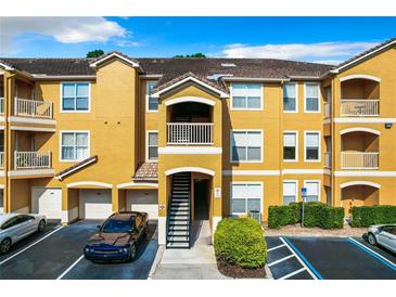 Three-story yellow condo building featuring private balconies and garage parking at 8818 Villa View Cir # 304, Orlando, FL 32821
