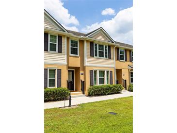 Inviting townhome with tan siding, dark shutters, manicured lawn, and well-maintained landscaping at 1255 Marley Ln, Winter Springs, FL 32708