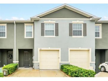 Two-story townhouse with gray facade, two-car garage, and manicured green shrubs at 1401 Yellow Finch Dr, Davenport, FL 33837