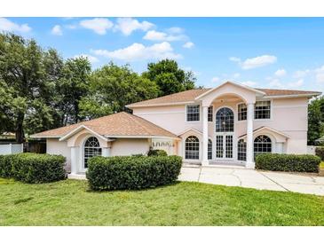 Two-story home featuring a manicured lawn, mature trees, and a circular driveway at 1802 Imperial Palm Dr, Apopka, FL 32712