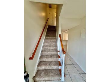 Carpeted staircase with wood railing leading to upper level, offering a bright and inviting entry at 316 Georgetown Dr, Casselberry, FL 32707