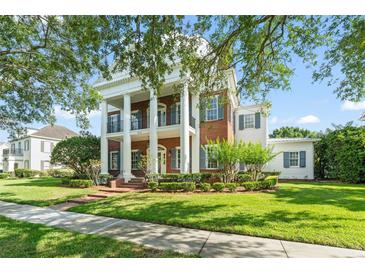 Stately brick home with white columns, black shutters, and lush landscaping at 506 Golfpark Dr, Celebration, FL 34747
