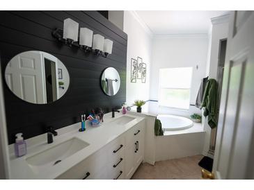 Modern bathroom featuring dual sinks, a soaking tub, and stylish black and white accents at 10255 Cody Ln, Orlando, FL 32825