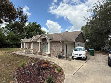 Charming single-story brick home featuring mature landscaping and a side-entry garage at 2120 Lakebreeze Way, Deltona, FL 32738