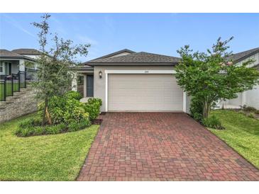 Charming single-Gathering home featuring a two-car garage, landscaped yard, and a beautiful brick driveway at 2241 Mystic Maze Ln, Minneola, FL 34715