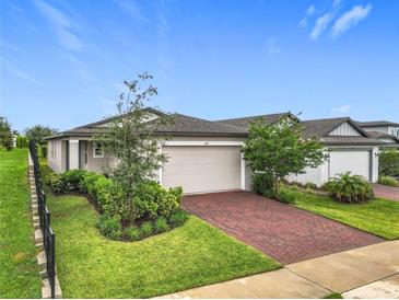 Charming single-Gathering home with a two-car garage, landscaped yard, and a beautiful red brick driveway at 2241 Mystic Maze Ln, Minneola, FL 34715