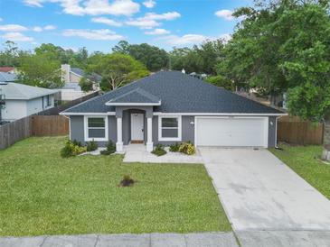 Well-maintained gray house with a dark roof, green lawn, and a two-car garage showcasing curb appeal at 2755 Abbey Ave, Orlando, FL 32833