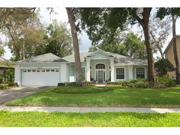 Charming one-story home with a light blue exterior, well-maintained lawn, and a two car garage at 4201 Old Trafford Way, Orlando, FL 32810