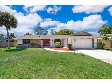 Charming single-story home with a well-manicured lawn, brick accents, red front door, and attached garage at 713 Coach Light Dr, Fern Park, FL 32730