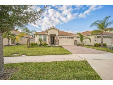 Charming single-story home featuring a well-manicured lawn, brick driveway, and a tile roof at 8907 Fallen Oak, Davenport, FL 33897