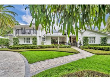 Stunning white home with manicured landscaping, a metal roof, and a second-story balcony offers luxurious curb appeal at 940 Lincoln Cir, Winter Park, FL 32789