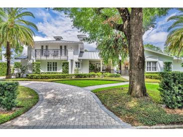 Beautiful home featuring a winding brick drive, lush landscaping, and a second-story balcony, offering great curb appeal at 940 Lincoln Cir, Winter Park, FL 32789