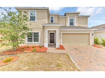 Inviting two-story home featuring a brick-paved driveway, attached two-car garage and manicured landscaping at 116 Green Branch Blvd, Groveland, FL 34736