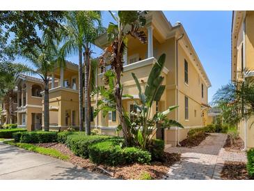 Charming yellow townhome featuring lush tropical landscaping and a welcoming entrance at 11918 Nautica Dr, Orlando, FL 32827