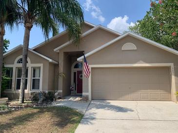 Charming single-Gathering home featuring a well-manicured lawn, a two-car garage, and mature palm trees in a quiet neighborhood at 1585 Stefan Cole Ln, Apopka, FL 32703