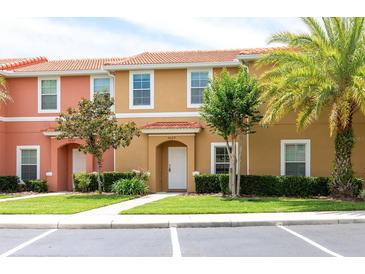 Inviting townhouse exterior featuring a terra cotta roof, well-kept lawn, and vibrant landscaping at 3069 White Orchid Rd, Kissimmee, FL 34747