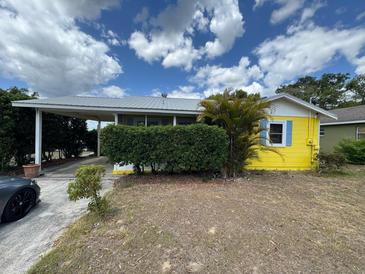 Charming home featuring a carport, yellow siding, and a nicely trimmed privacy hedge at 825 Poinsettia Dr, Eustis, FL 32726