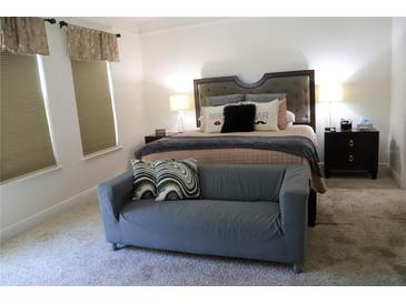 Bright bedroom featuring a gray settee, plush carpet, and a comfortable king-size bed at 9005 Reflection Pointe Dr, Windermere, FL 34786