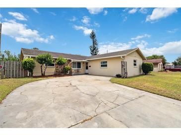 Charming single-story home with a circular driveway and well-maintained landscaping under a bright, cloudy sky at 10934 Tangora St, Orlando, FL 32825