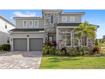 Beautiful two-story home featuring a two-car garage, stone accents, and a meticulously manicured lawn at 16124 Volterra Pt, Montverde, FL 34756