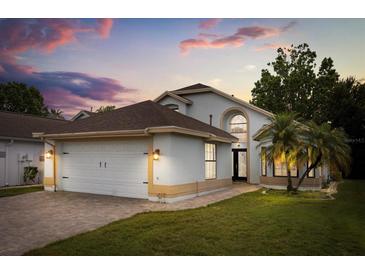 Charming single-Gathering home with a well-manicured lawn, two car garage, and tropical landscaping against a colorful sunset sky at 5672 Parkview Lake Dr, Orlando, FL 32821